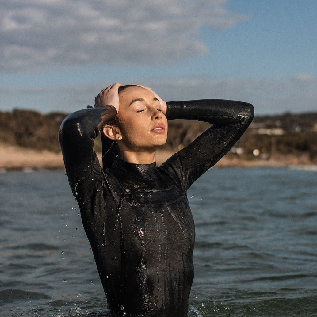 Woman pulling hair back in the ocean