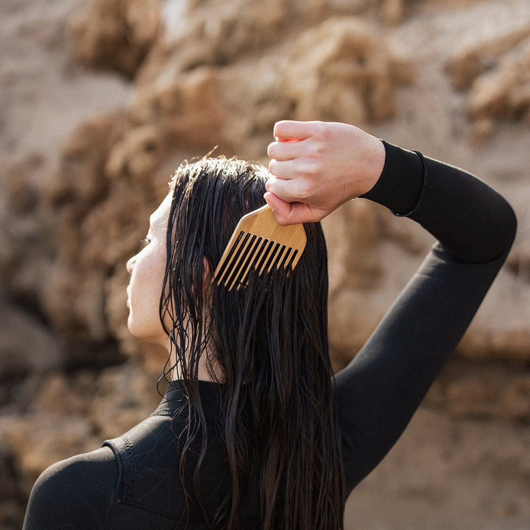 Woman using eco bamboo comb in wet hair.